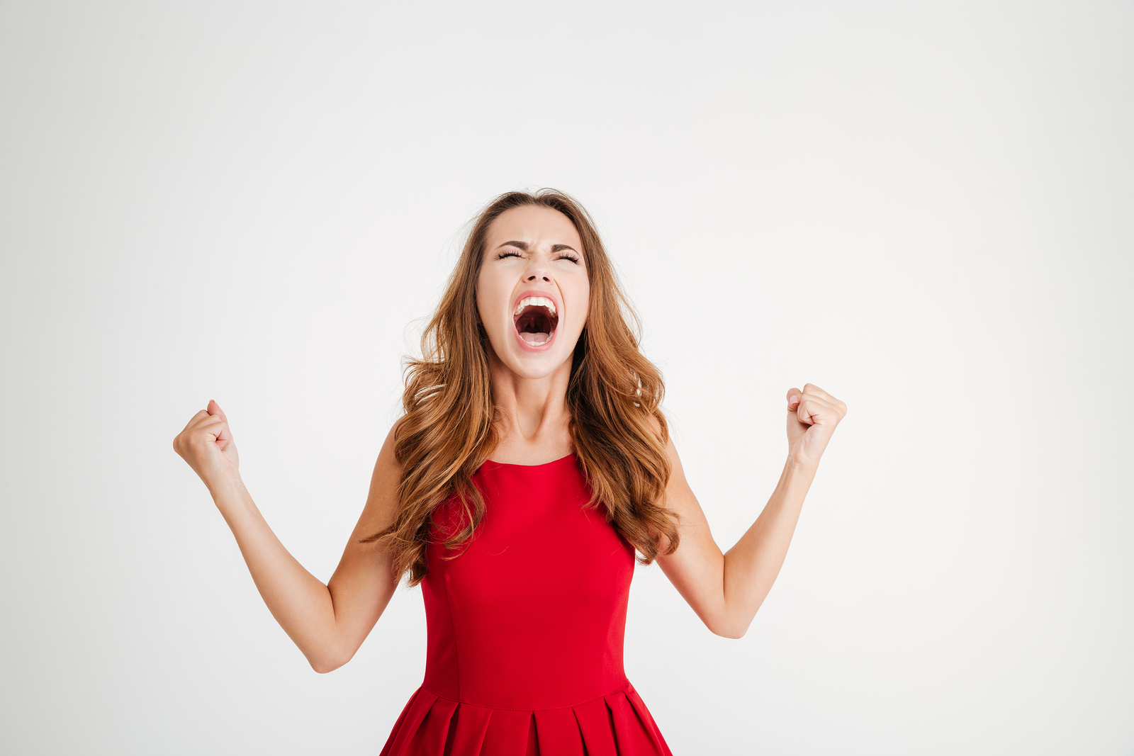 Mad furious young woman with raised hands standing and screaming