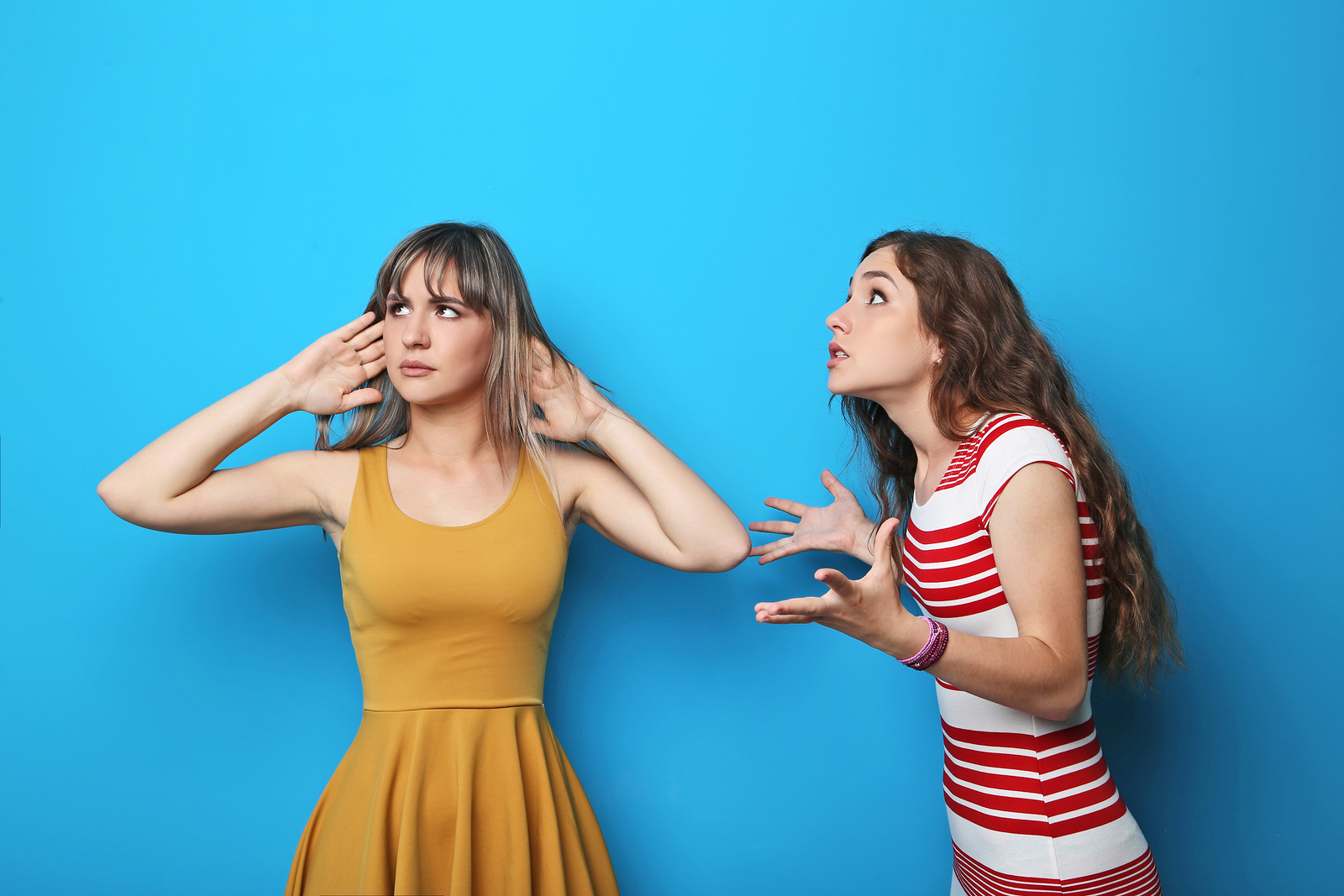 Two young woman having an argue on blue background